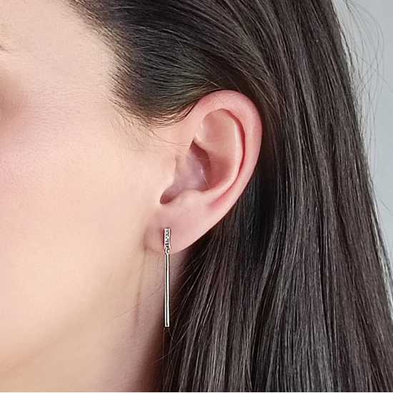 De diseño especialmente minimalista, donde de una pequeña barrita de 6,4mm cuajada con cuatro pequeñas circonitas blancas cuelga